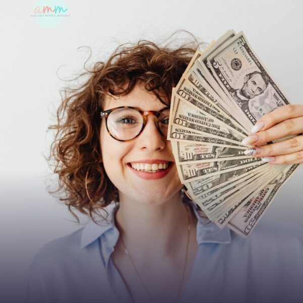 Smiling woman holding cash to symbolize confidence, financial clarity, and the impact of making empowered money decisions.